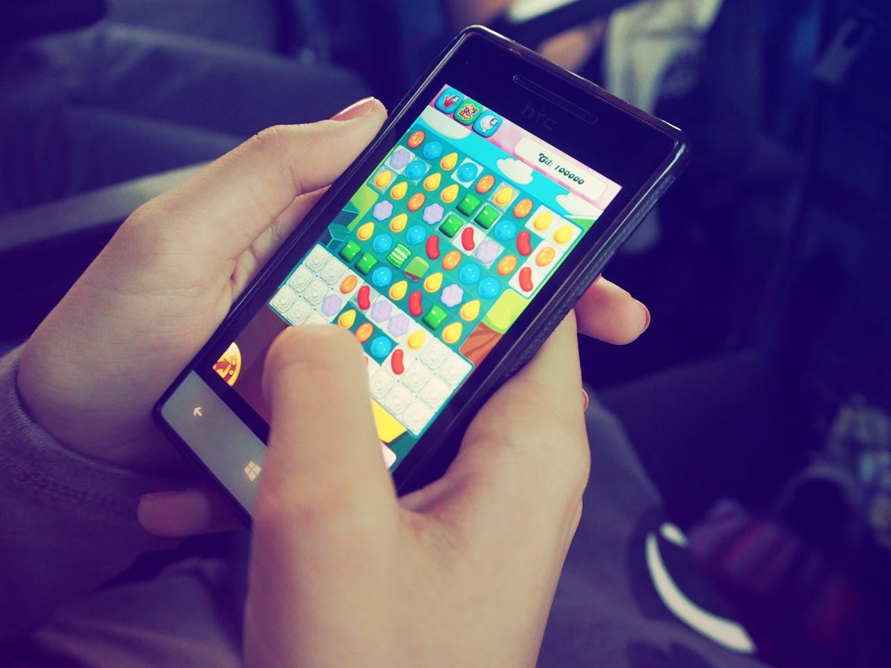 about-03 Hands holding a smartphone with a colorful puzzle game on the screen, displaying modern technology.